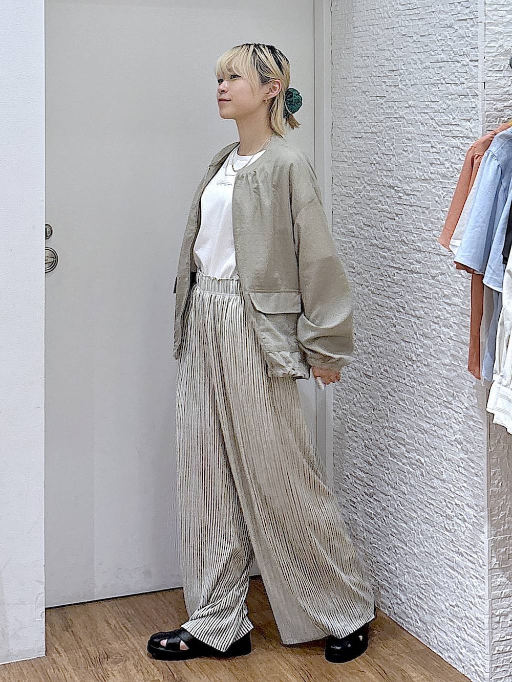 グリーン系のブルゾン、ホワイト系のTシャツ/カットソー、ブラック系のサンダルを着用したレディースの夏コーディネートの2枚目の写真