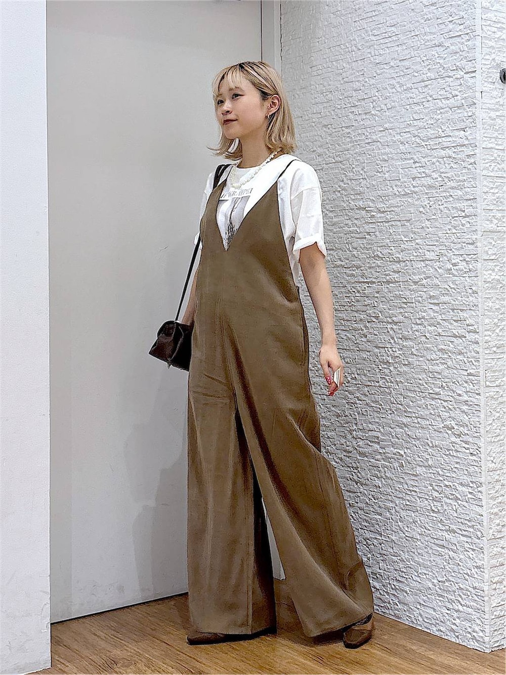 ブラウン系のショルダーバッグ、ホワイト系のTシャツ/カットソー、ブラウン系のパンプスを着用したレディースの夏コーディネートの2枚目の写真