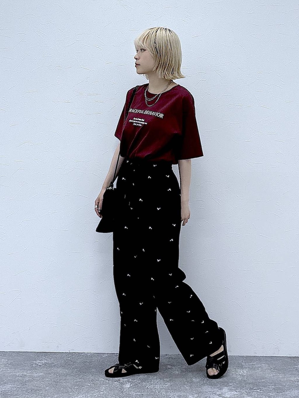 レッド系のTシャツ/カットソー、ブラック系のその他パンツ、ブラック系のサンダルを着用したレディースの夏コーディネートの2枚目の写真