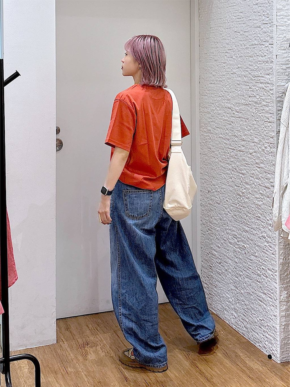 ベージュ系のスニーカー、ベージュ系のショルダーバッグ、ブルー系のデニムパンツを着用したレディースの夏コーディネートの3枚目の写真