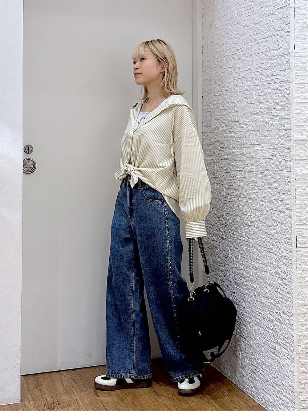 ブルー系のデニムパンツ、ブラック系のスニーカー、グレー系のタンクトップを着用したレディースの夏コーディネートの2枚目の写真