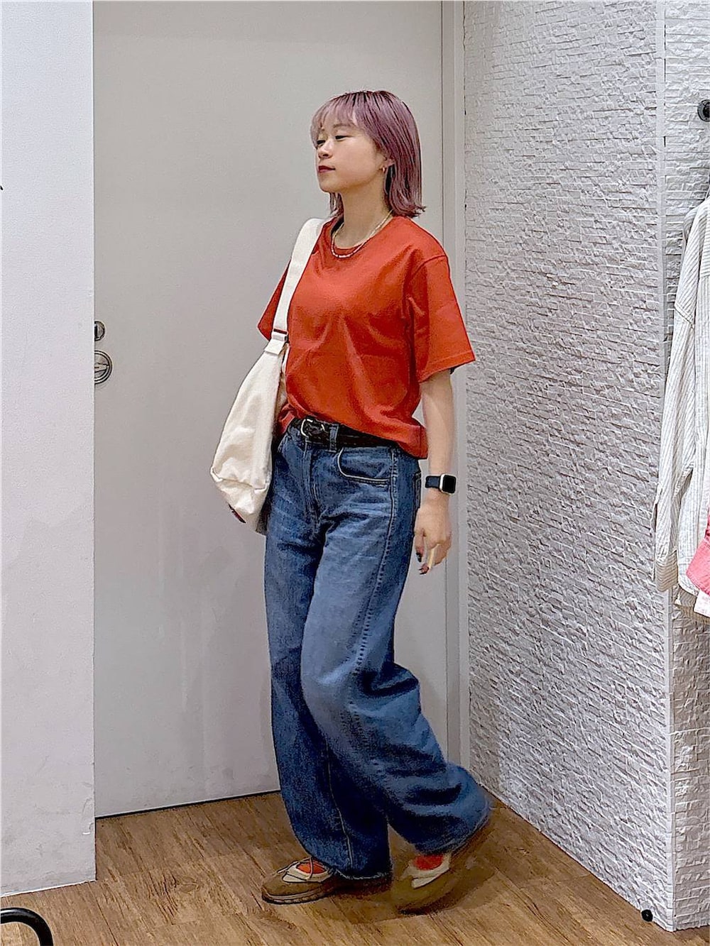 ベージュ系のスニーカー、ベージュ系のショルダーバッグ、ブルー系のデニムパンツを着用したレディースの夏コーディネートの2枚目の写真
