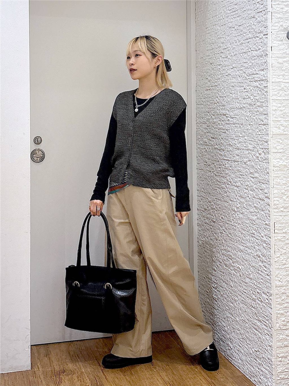 ブラック系のトートバッグ、ブラック系のTシャツ/カットソー、ブラック系のベストを着用したレディースの秋コーディネートの2枚目の写真