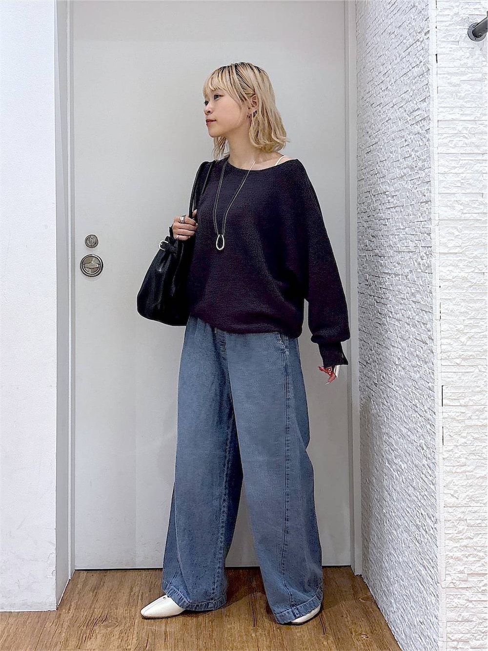 ベージュ系のパンプス、ブラック系のボストンバッグ、グレー系のニット/セーターを着用したレディースの夏コーディネートの2枚目の写真