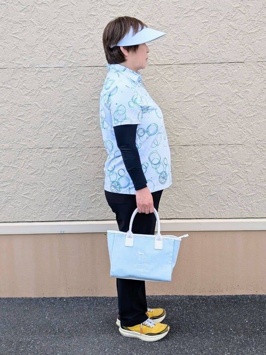 ブルー系のポロシャツ、ブラック系のその他パンツ、ホワイト系のサンバイザーを着用したレディースの春コーディネートの3枚目の写真
