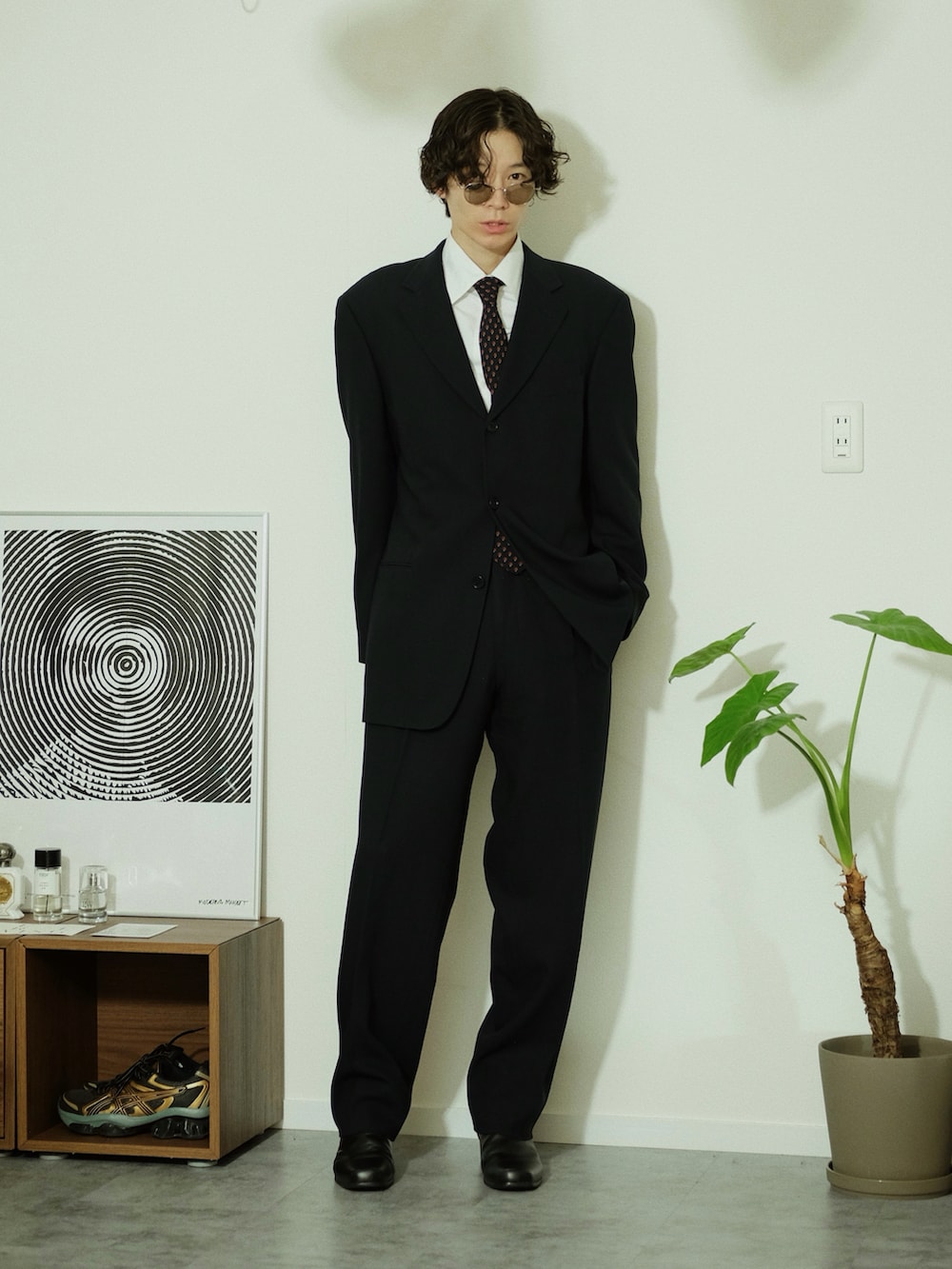 ブラック系のスーツセット、ブラック系のブーツ、ゴールド系のサングラスを着用したメンズの冬コーディネートの2枚目の写真