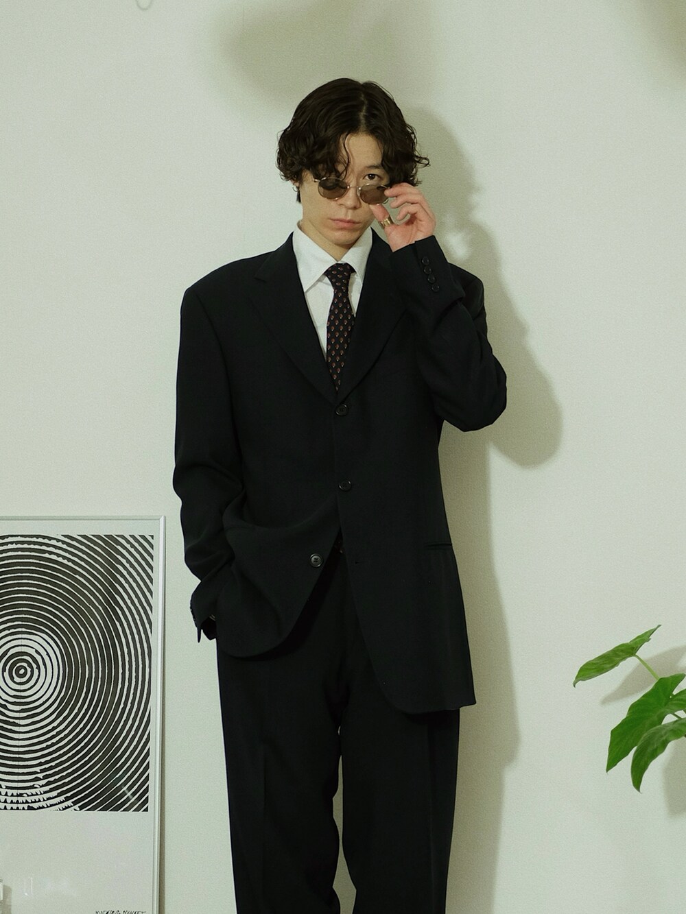 ブラック系のスーツセット、ブラック系のブーツ、ゴールド系のサングラスを着用したメンズの冬コーディネートの5枚目の写真