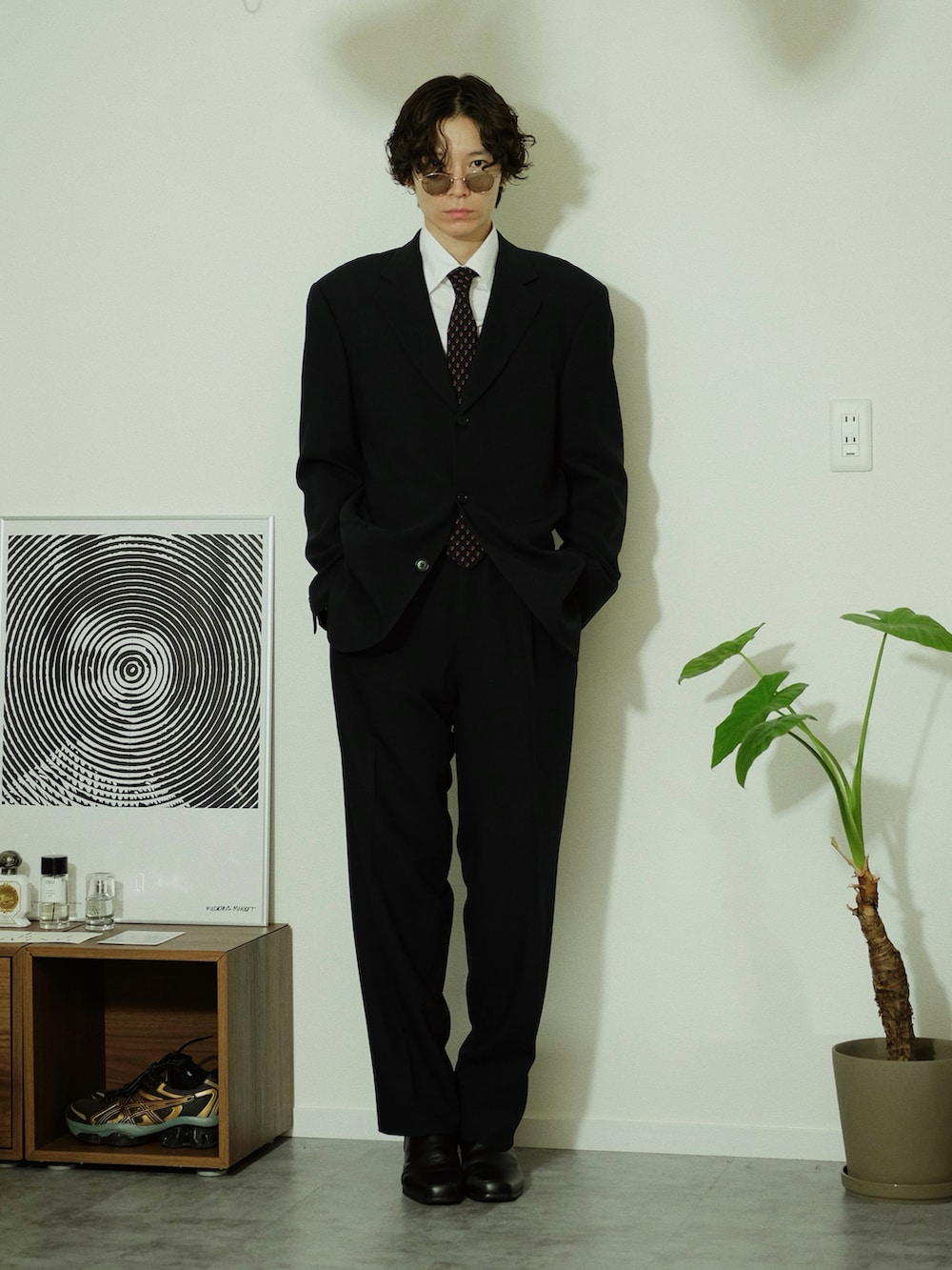 ブラック系のスーツセット、ブラック系のブーツ、ゴールド系のサングラスを着用したメンズの冬コーディネートの4枚目の写真