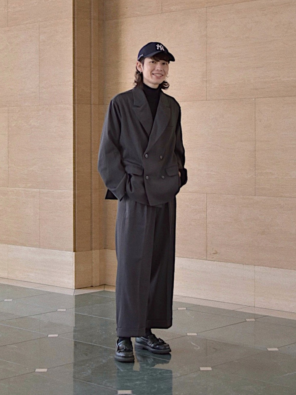 グレー系のテーラードジャケット、グレー系のスラックス、ブラック系のニット/セーターを着用したメンズの冬コーディネートの3枚目の写真