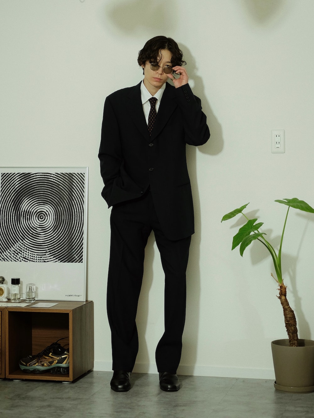 ブラック系のスーツセット、ブラック系のブーツ、ゴールド系のサングラスを着用したメンズの冬コーディネートの3枚目の写真