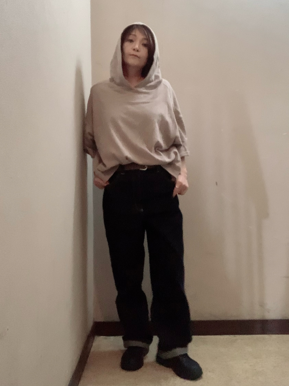 ベージュ系のパーカー、ブルー系のデニムパンツ、ブラック系のブーツを着用したレディースの秋コーディネートの2枚目の写真