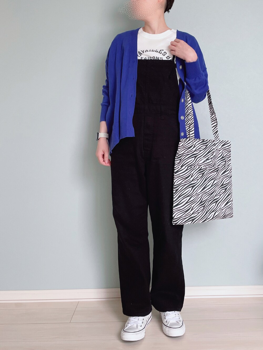 ブラック系のサロペット/オーバーオール、ブルー系のカーディガン/ボレロ、ホワイト系のTシャツ/カットソーを着用したレディースの春コーディネートの2枚目の写真