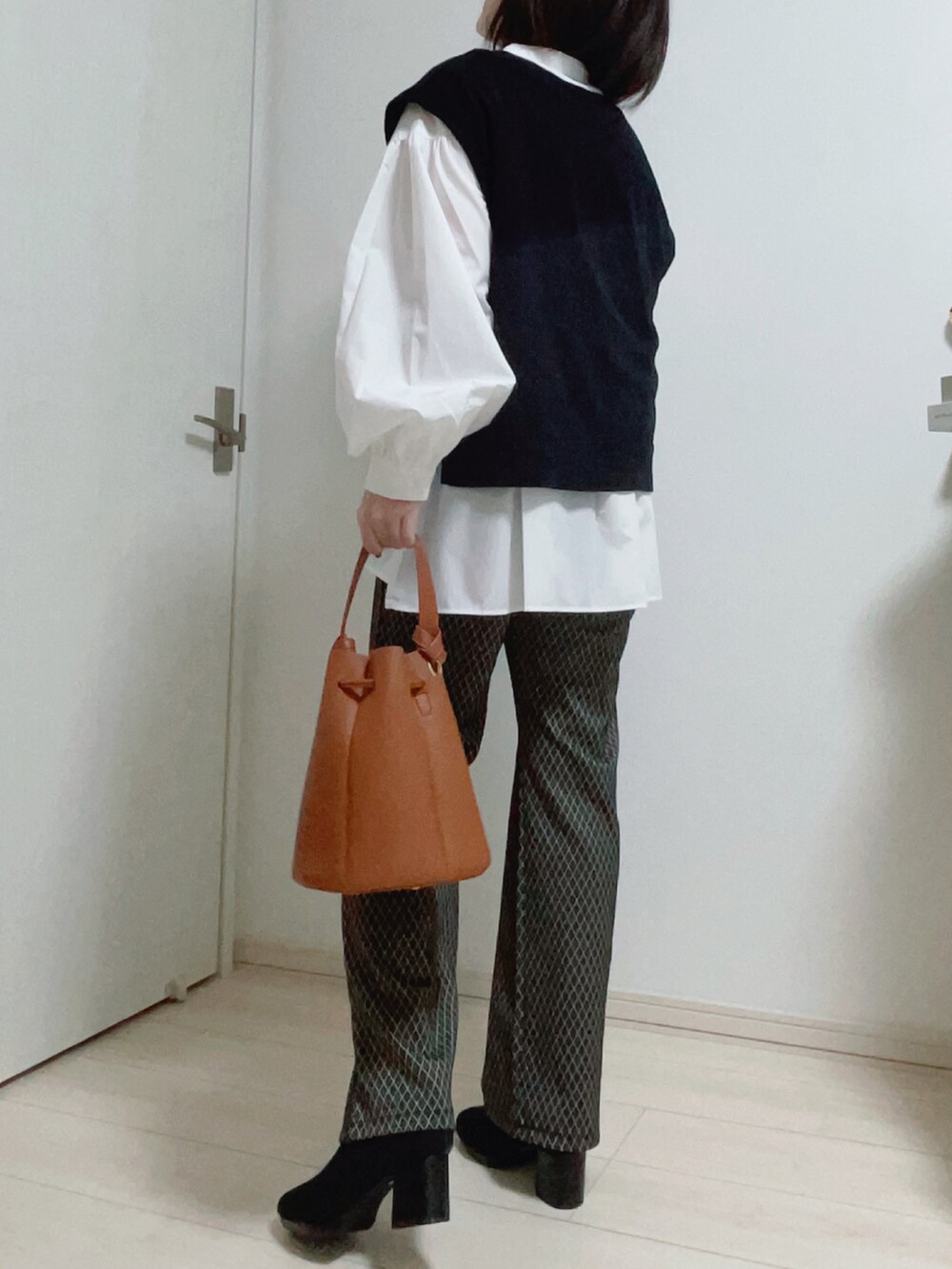 ブラック系のベスト、ホワイト系のシャツ/ブラウス、ブラック系のその他パンツを着用したレディースの秋コーディネートの2枚目の写真