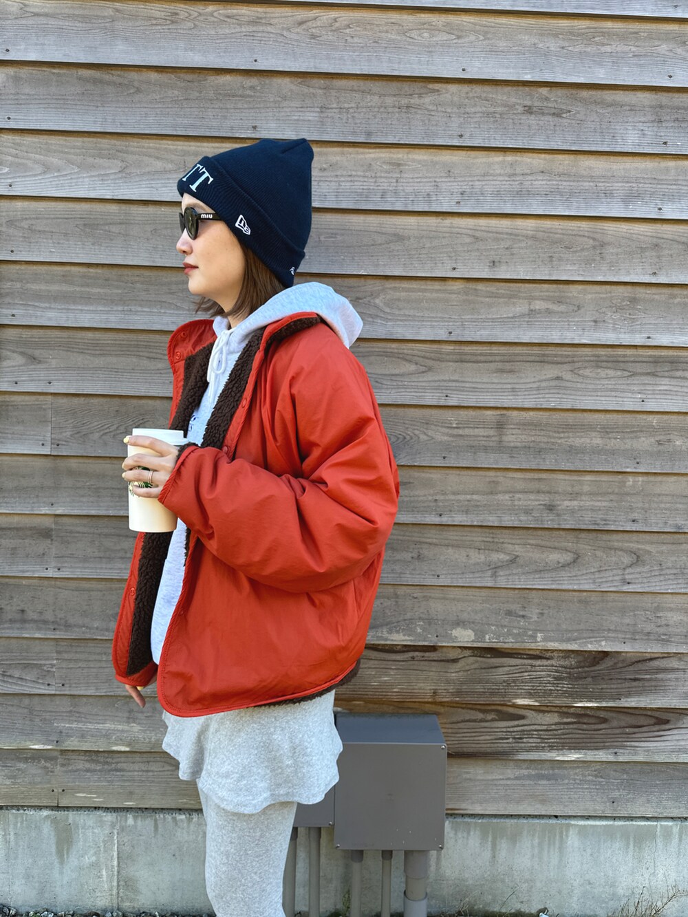 グレー系のスカート、ブラック系のブーツ、オレンジ系のジャケット/アウターを着用したレディースの冬コーディネートの4枚目の写真