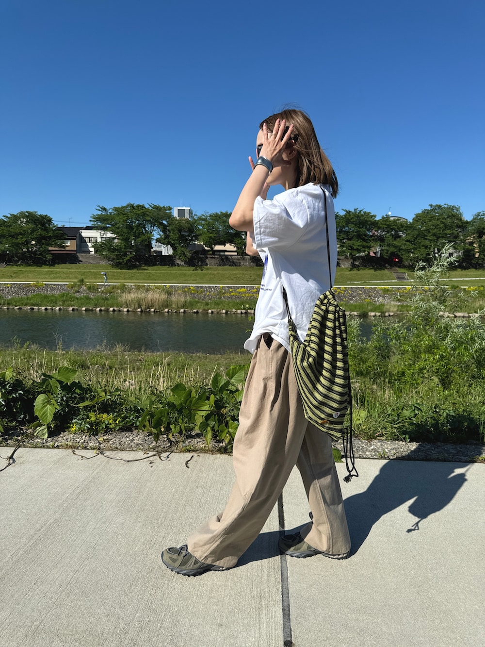 ホワイト系のTシャツ/カットソー、ベージュ系のパンツ、グリーン系のスニーカーを着用したレディースの春コーディネートの2枚目の写真