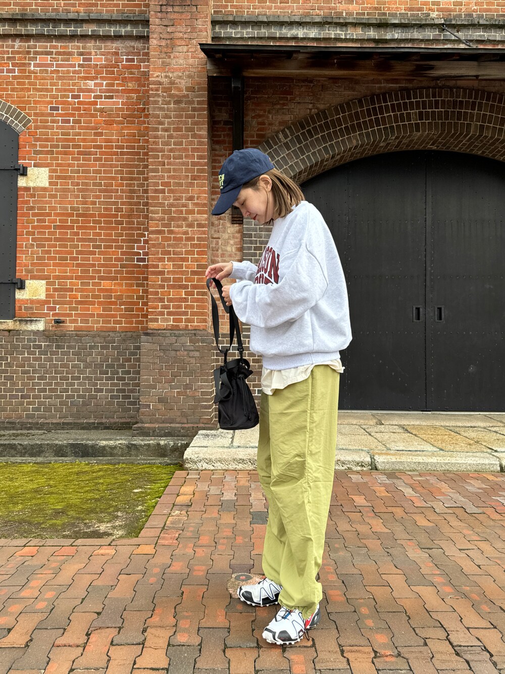 グリーン系のパンツ、グレー系のスウェット、ブラック系のバッグを着用したレディースの春コーディネートの4枚目の写真