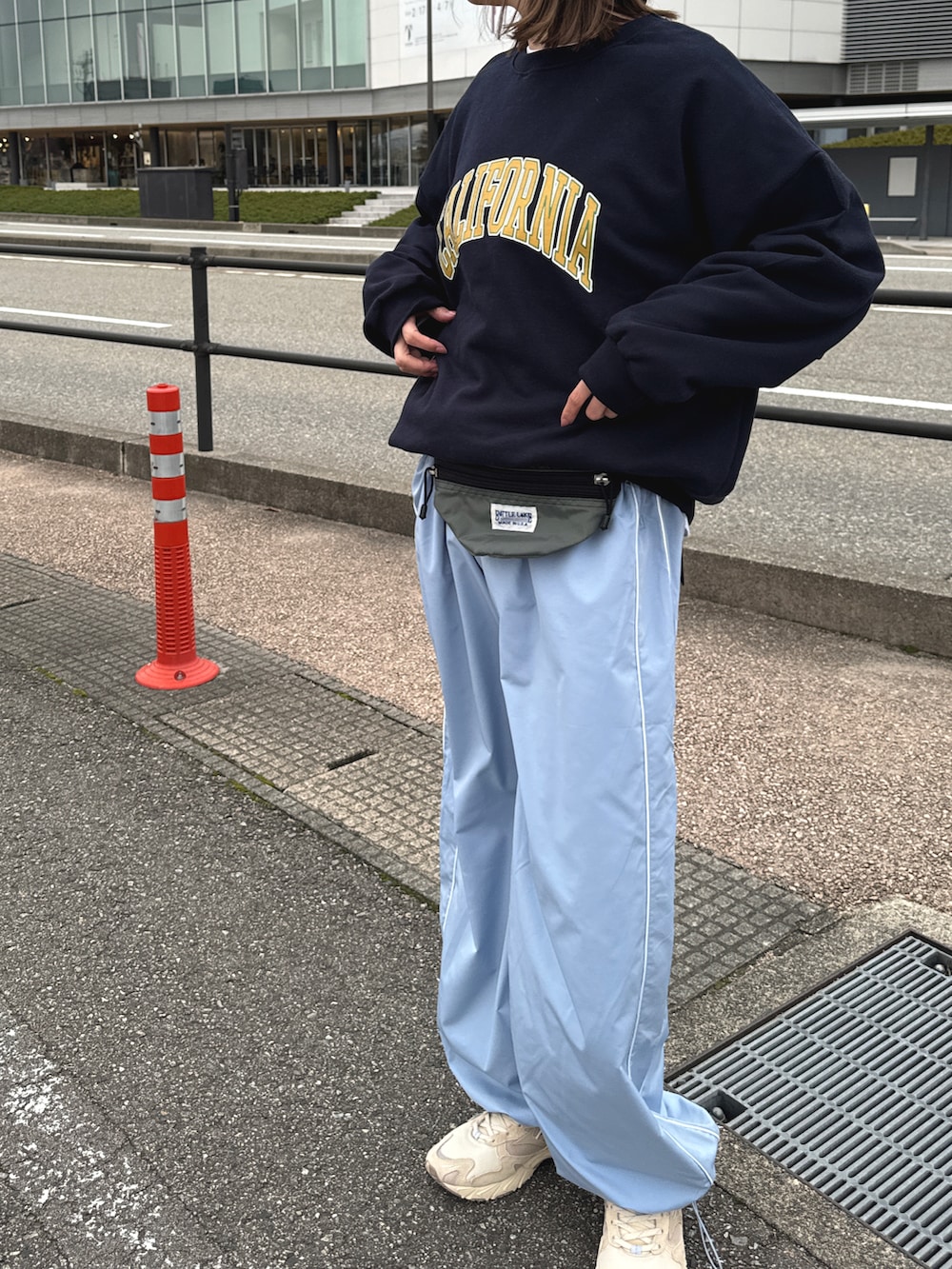 ベージュ系のスニーカー、ブルー系のパンツ、グレー系のボディバッグ/ウエストポーチを着用したレディースの春コーディネートの2枚目の写真