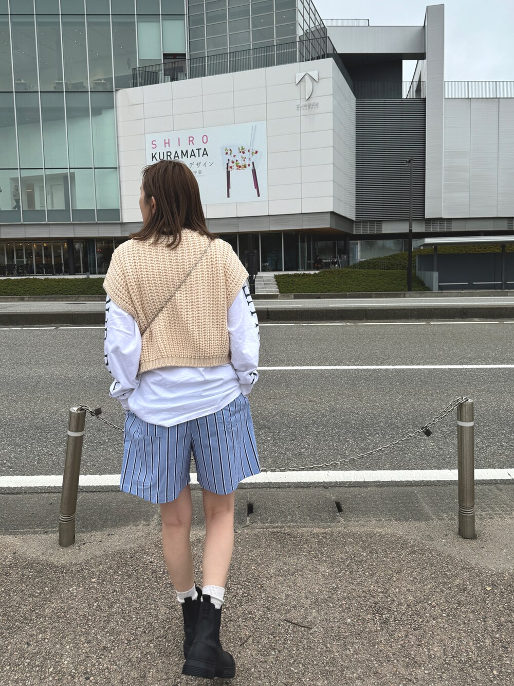 ブラック系のブーツ、ブルー系のパンツ、ホワイト系のトップスを着用したレディースの冬コーディネートの2枚目の写真