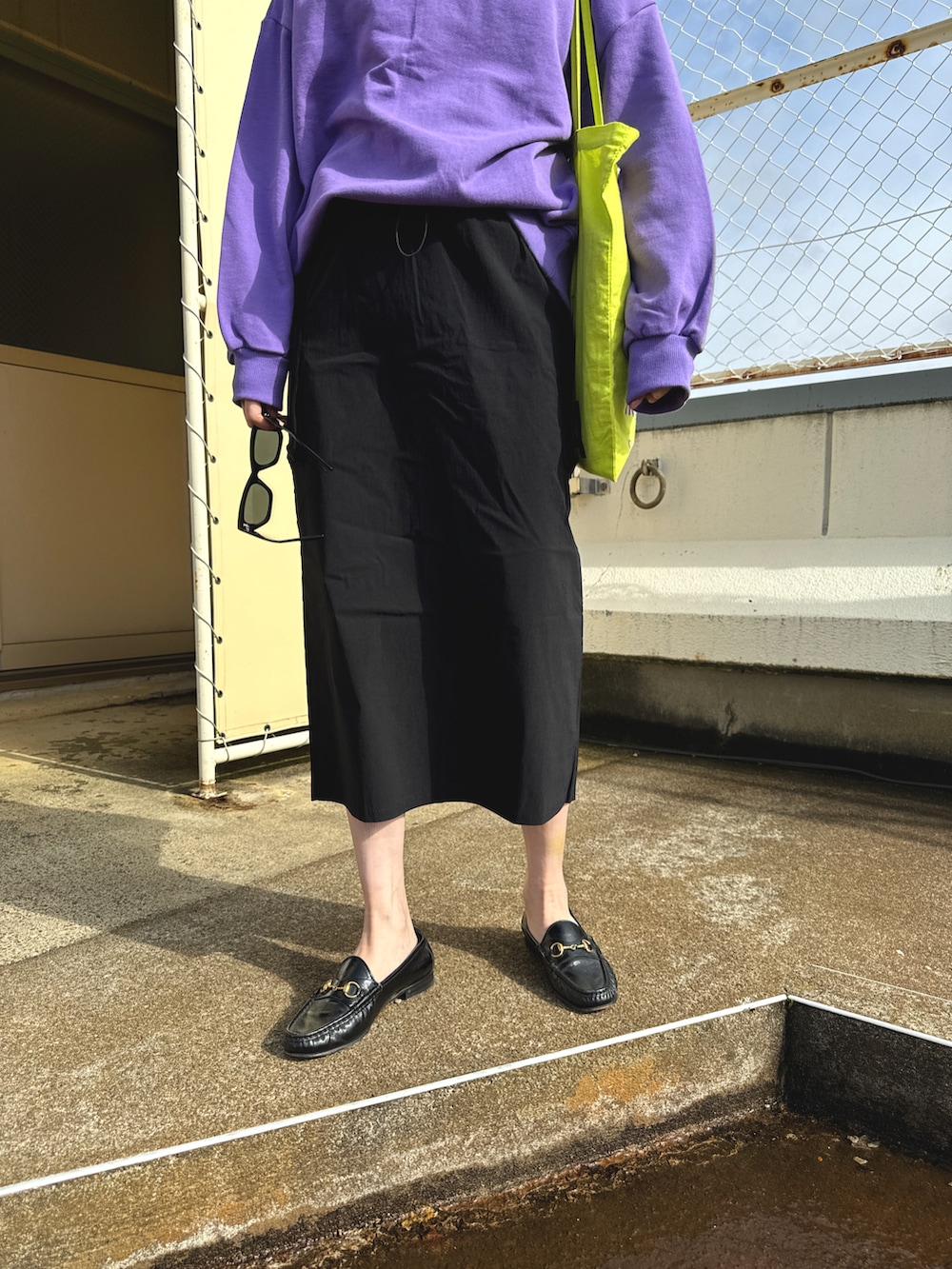 イエロー系のトートバッグ、パープル系のスウェット、ブラック系のスカートを着用したレディースの春コーディネートの5枚目の写真