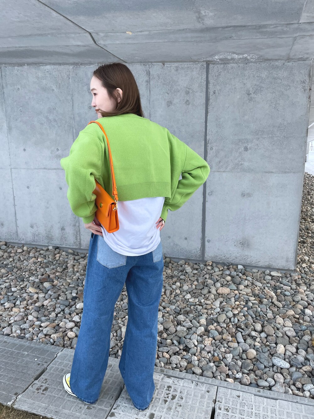 ブルー系のデニムパンツ、グリーン系のカーディガン/ボレロ、イエロー系のスニーカーを着用したレディースの冬コーディネートの2枚目の写真