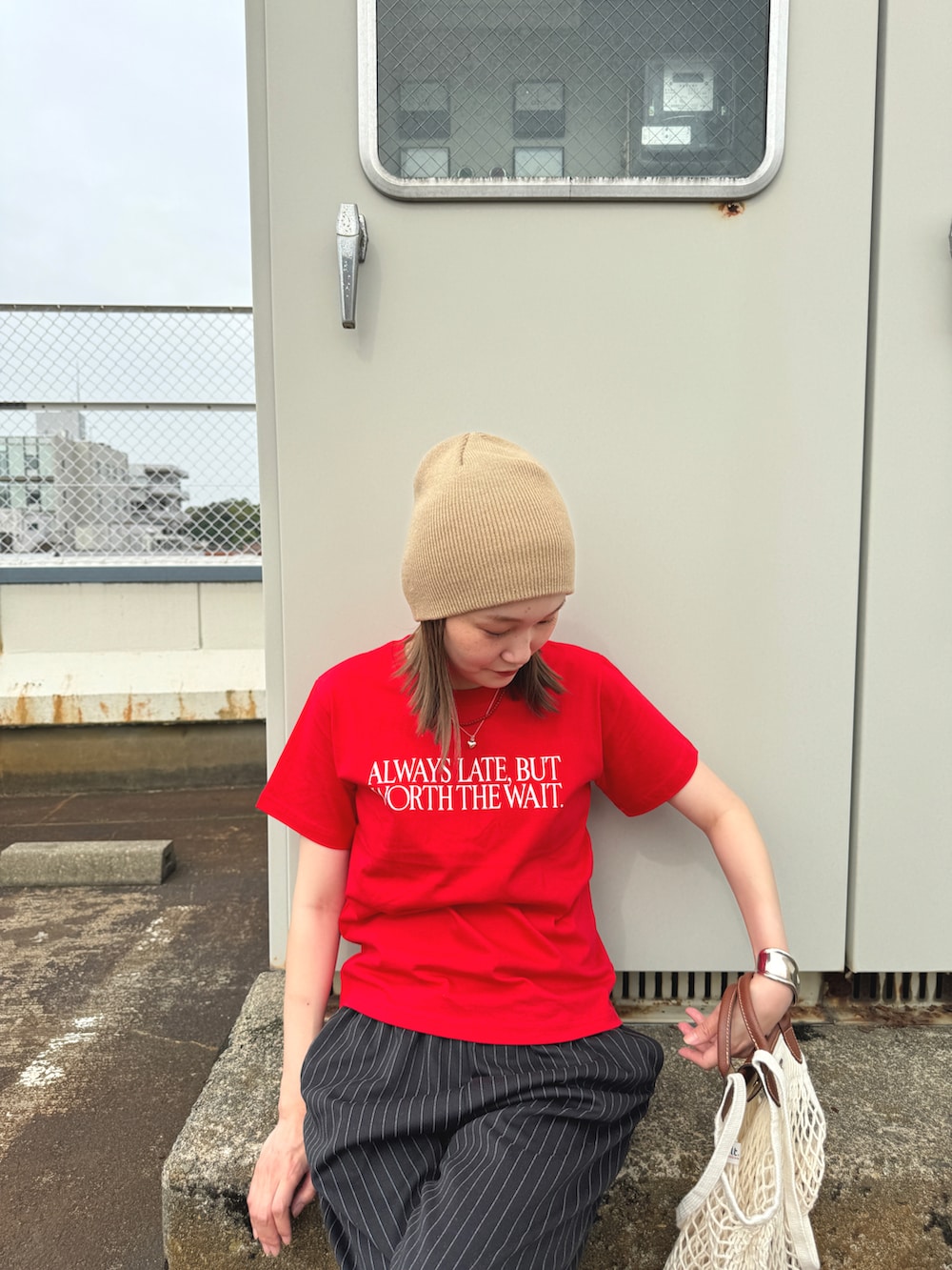 レッド系のTシャツ/カットソー、ブラック系のパンツ、ホワイト系のスニーカーを着用したレディースの夏コーディネートの3枚目の写真
