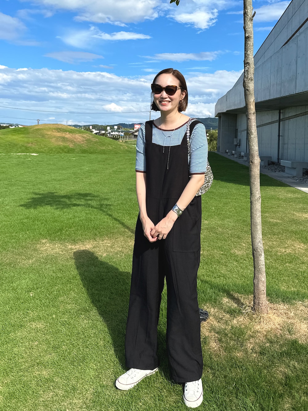 ブラック系のオールインワン・サロペット、ブルー系のトップス、シルバー系のバッグを着用したレディースの秋コーディネートの2枚目の写真