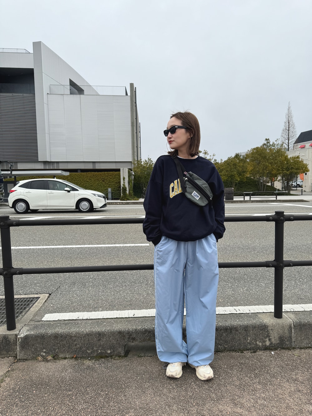 ベージュ系のスニーカー、ブルー系のパンツ、グレー系のボディバッグ/ウエストポーチを着用したレディースの春コーディネートの4枚目の写真