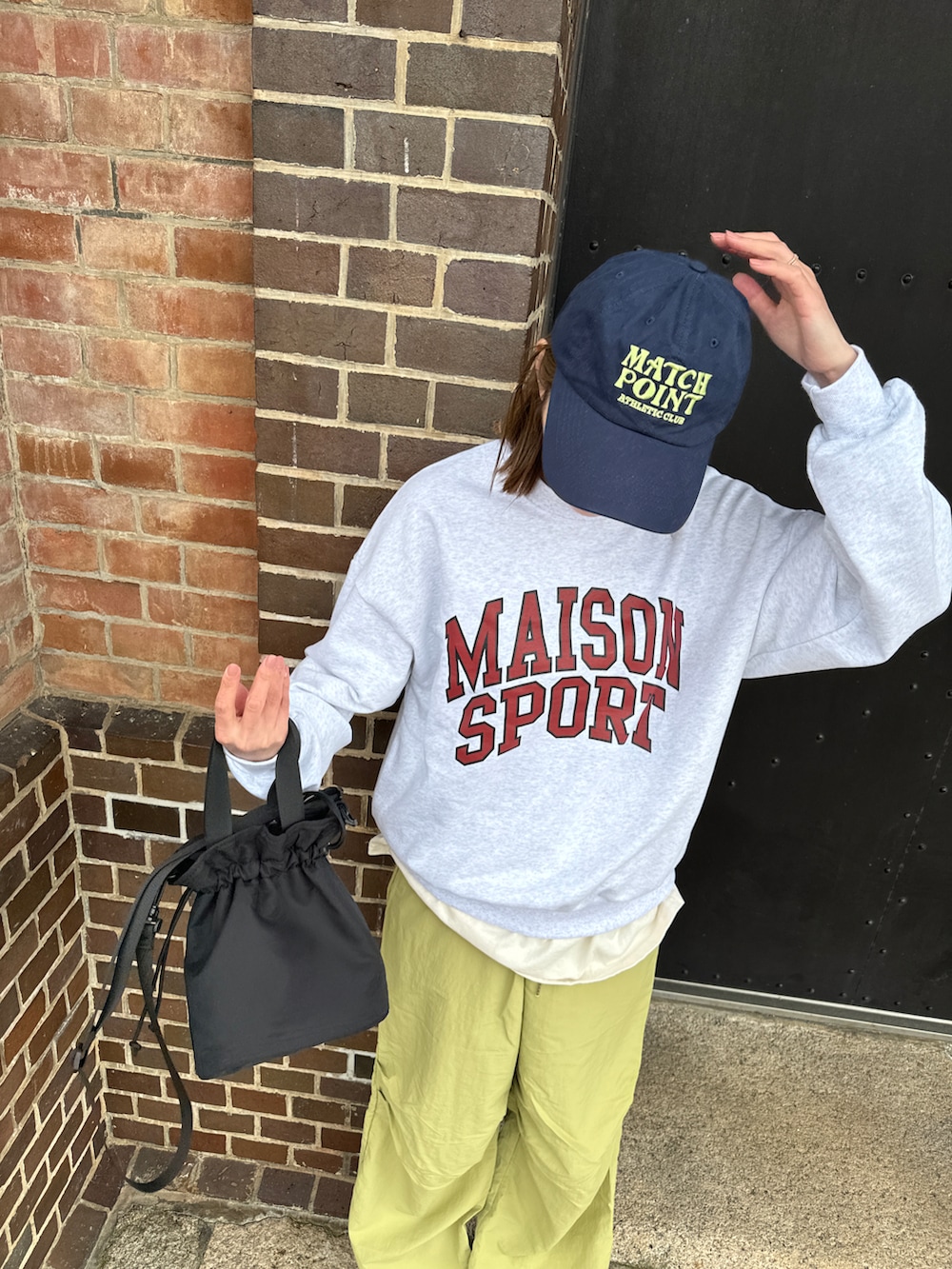 グリーン系のパンツ、グレー系のスウェット、ブラック系のバッグを着用したレディースの春コーディネートの3枚目の写真