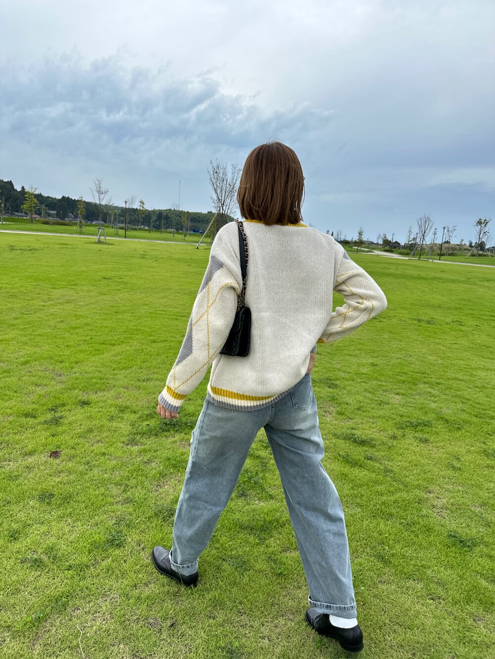 ブルー系のデニムパンツ、ベージュ系のニット/セーター、ブラウン系のメガネを着用したレディースの秋コーディネートの4枚目の写真