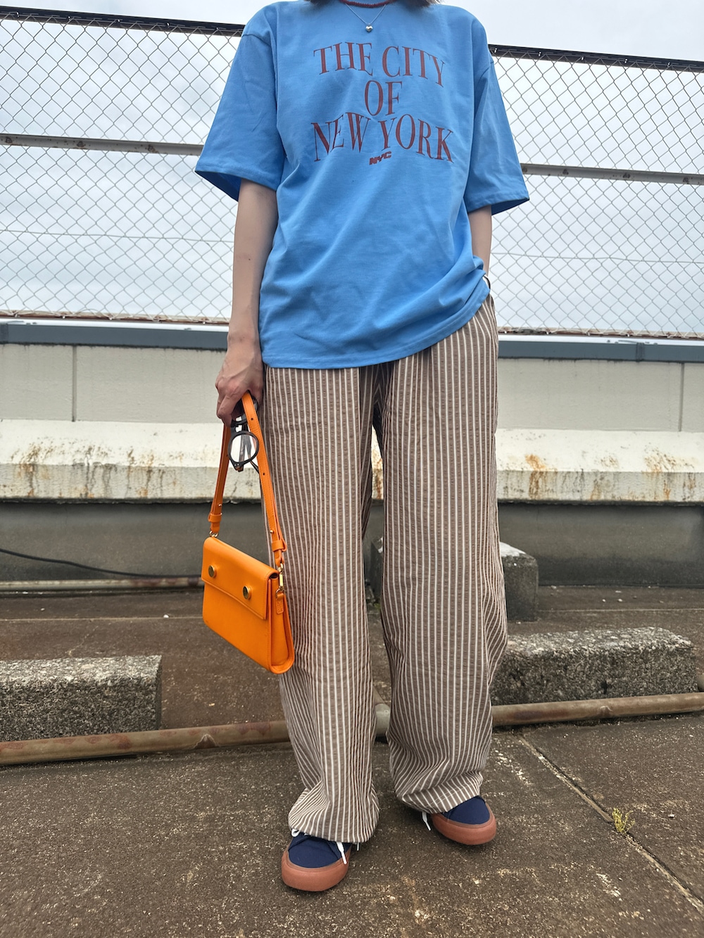 ブルー系のTシャツ/カットソー、ブラウン系のパンツ、ブラウン系のメガネを着用したレディースの春コーディネートの2枚目の写真