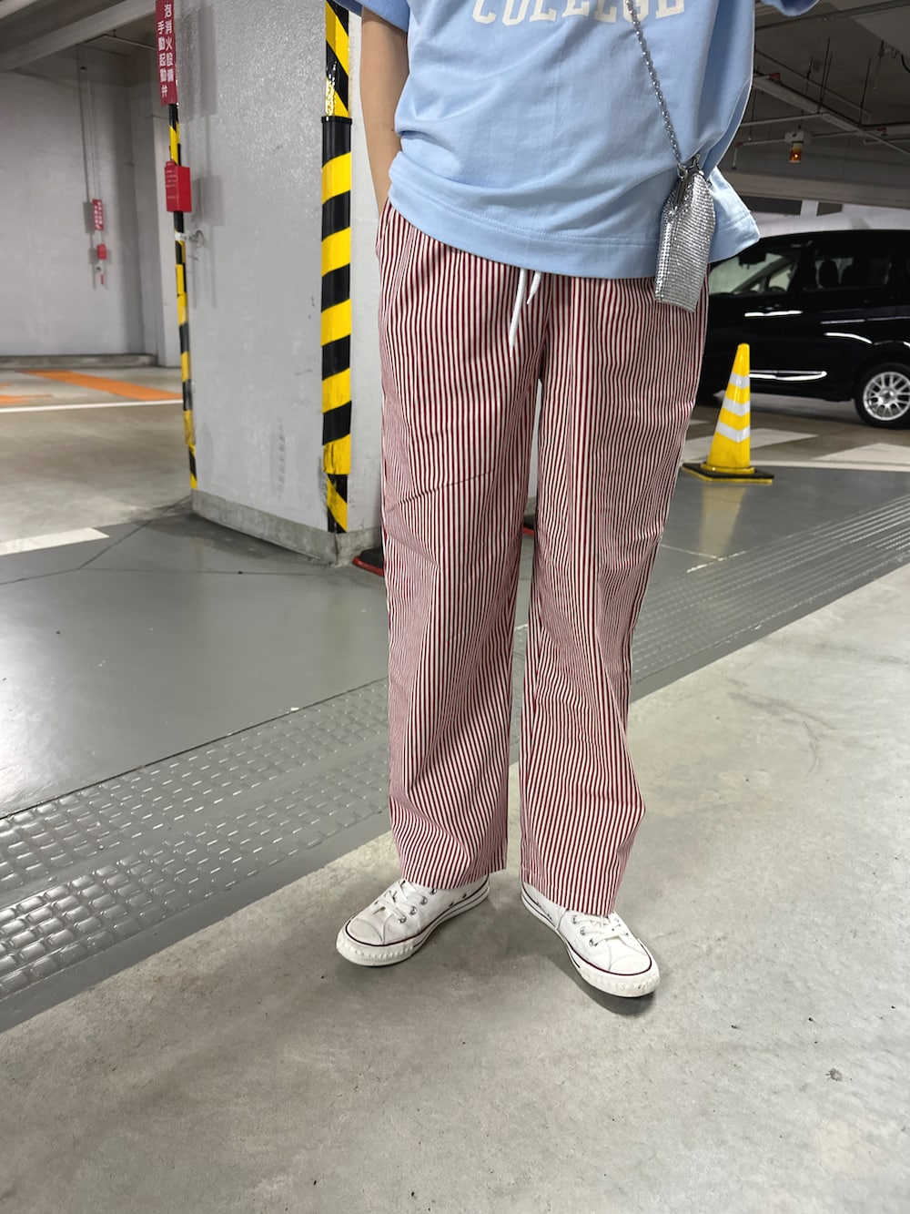 レッド系のパンツ、シルバー系のバッグ、ブルー系のトップスを着用したレディースの春コーディネートの2枚目の写真