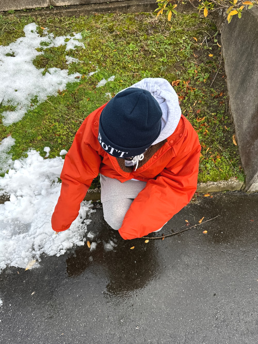 グレー系のスカート、ブラック系のブーツ、オレンジ系のジャケット/アウターを着用したレディースの冬コーディネートの2枚目の写真