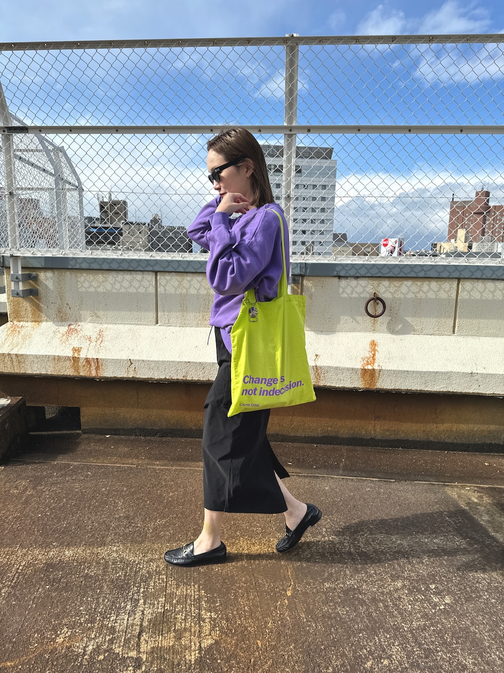 イエロー系のトートバッグ、パープル系のスウェット、ブラック系のスカートを着用したレディースの春コーディネートの3枚目の写真