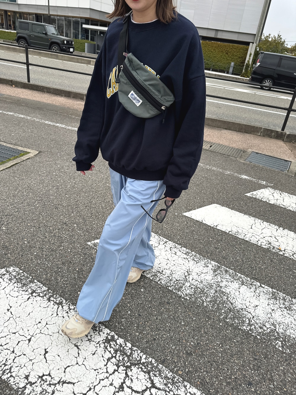 ベージュ系のスニーカー、ブルー系のパンツ、グレー系のボディバッグ/ウエストポーチを着用したレディースの春コーディネートの3枚目の写真