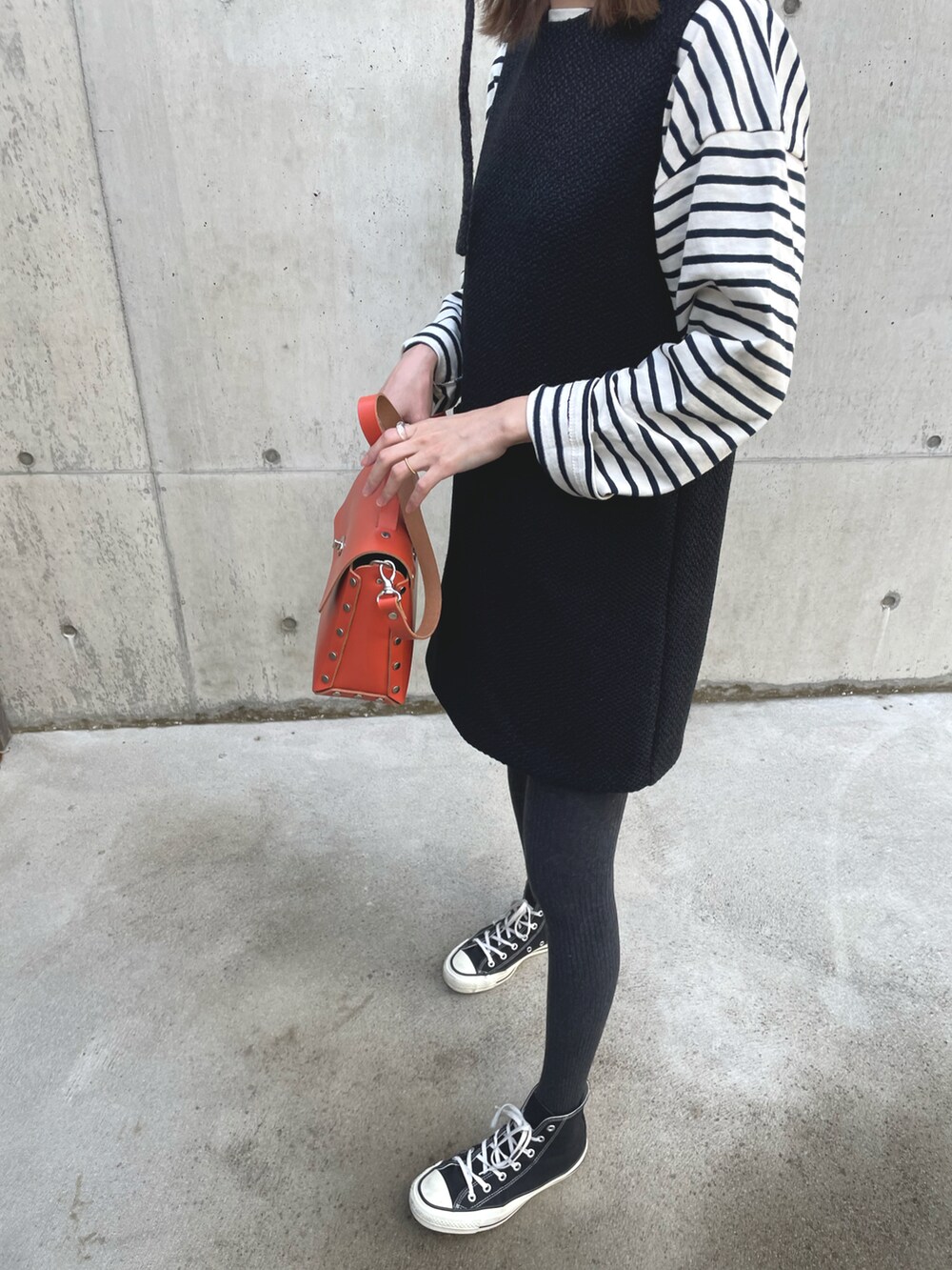 オレンジ系のバッグ、ブラック系のワンピース/ドレス、ブラック系のスニーカーを着用したレディースの冬コーディネートの3枚目の写真