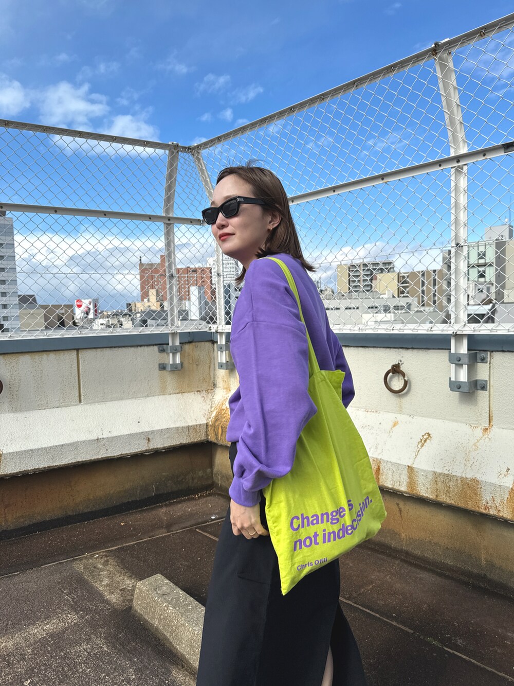 イエロー系のトートバッグ、パープル系のスウェット、ブラック系のスカートを着用したレディースの春コーディネートの2枚目の写真