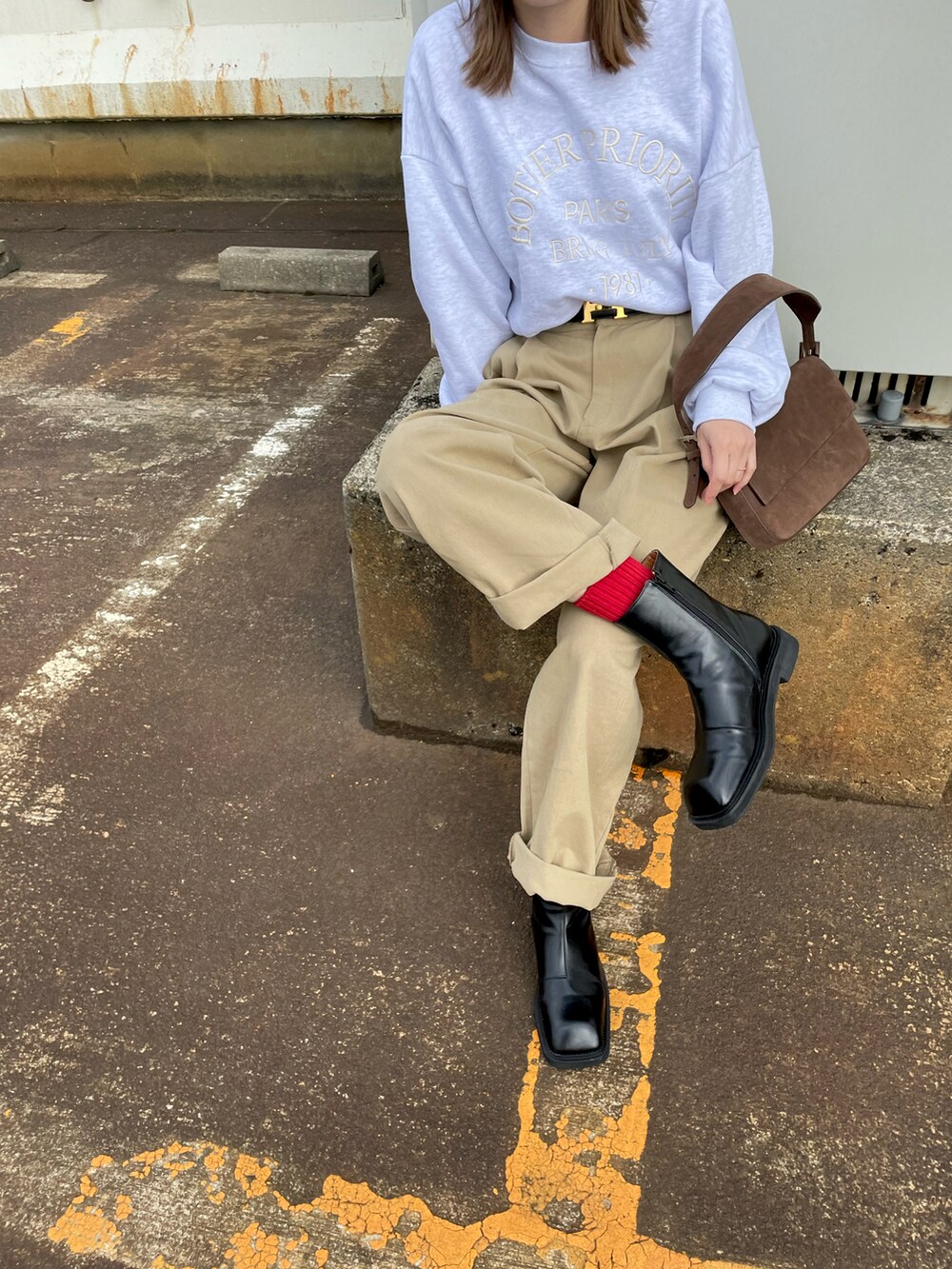 ベージュ系のチノパンツ、ブラック系のブーツ、グレー系のスウェットを着用したレディースの冬コーディネートの3枚目の写真