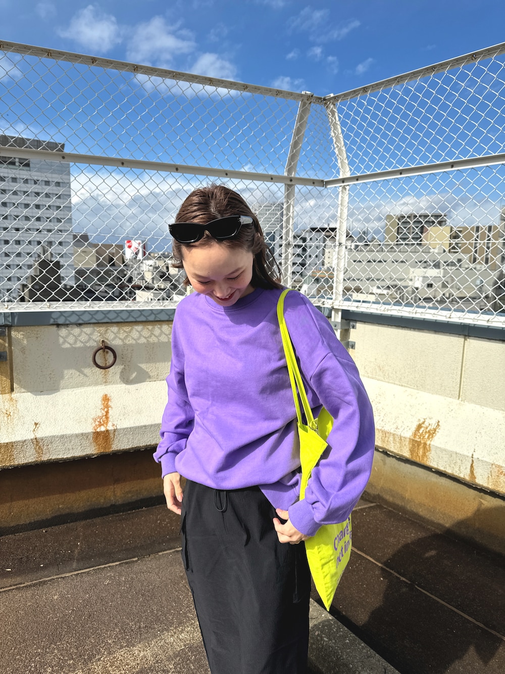 イエロー系のトートバッグ、パープル系のスウェット、ブラック系のスカートを着用したレディースの春コーディネートの4枚目の写真