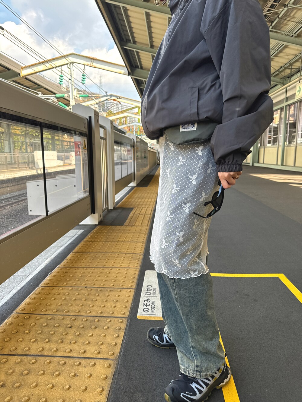 ブルー系のデニムパンツ、グレー系のジャケット/アウター、ホワイト系のスカートを着用したレディースの冬コーディネートの2枚目の写真