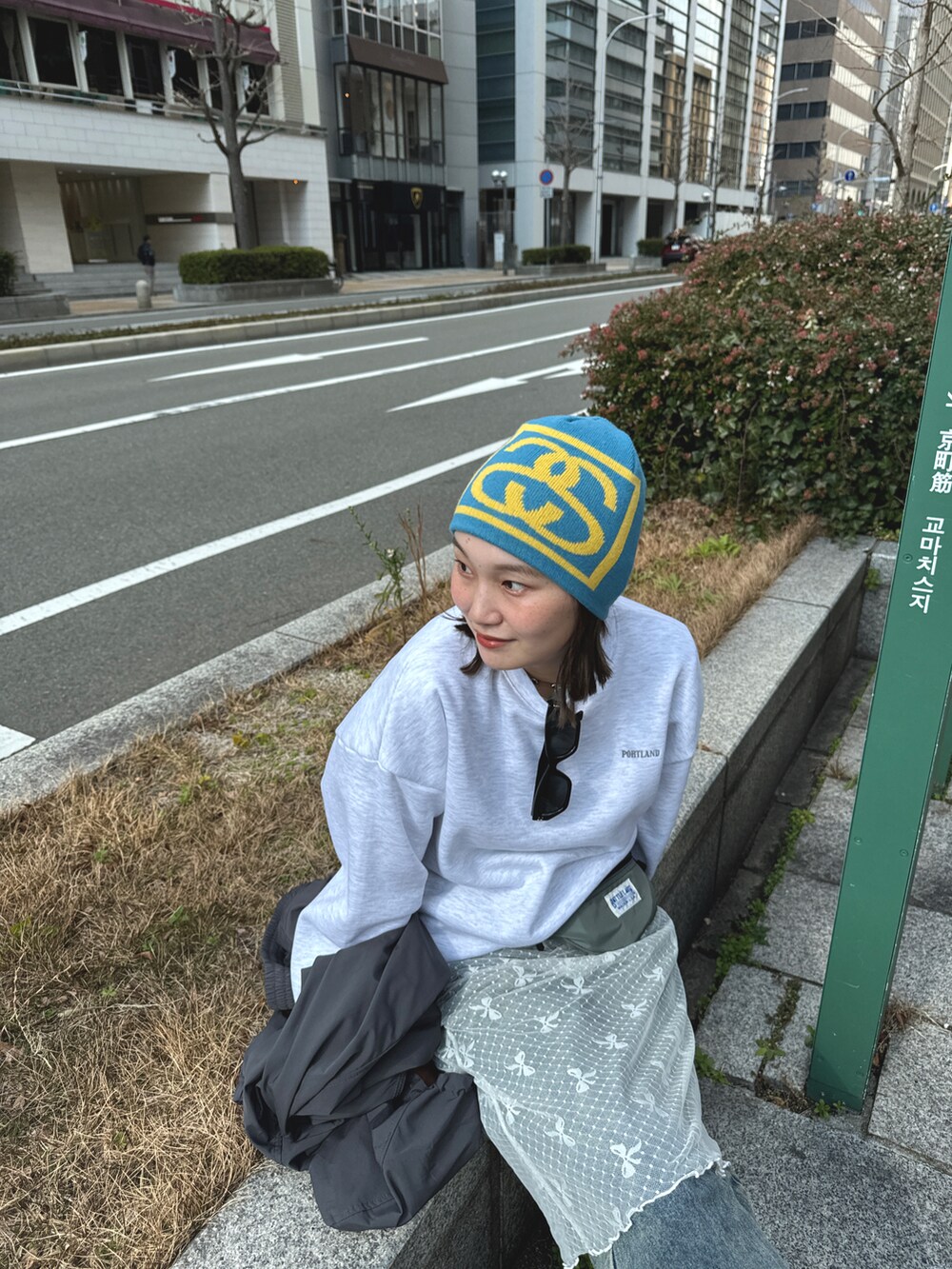 グレー系のスウェット、ホワイト系のスカート、ブルー系のデニムパンツを着用したレディースの冬コーディネートの3枚目の写真