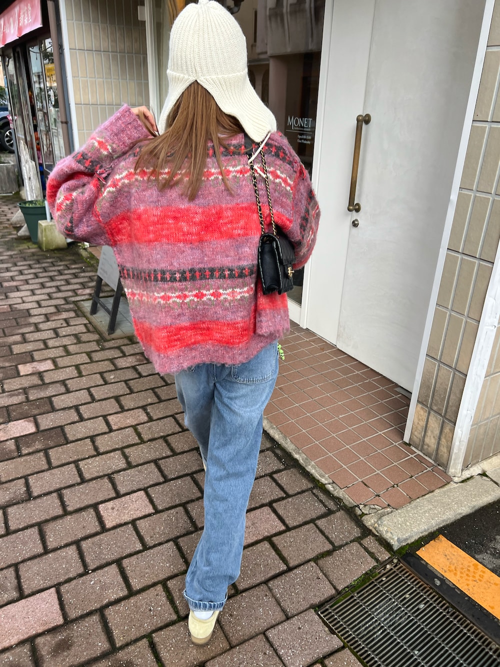 レッド系のカーディガン/ボレロ、ベージュ系のブーツを着用したレディースの秋コーディネートの2枚目の写真