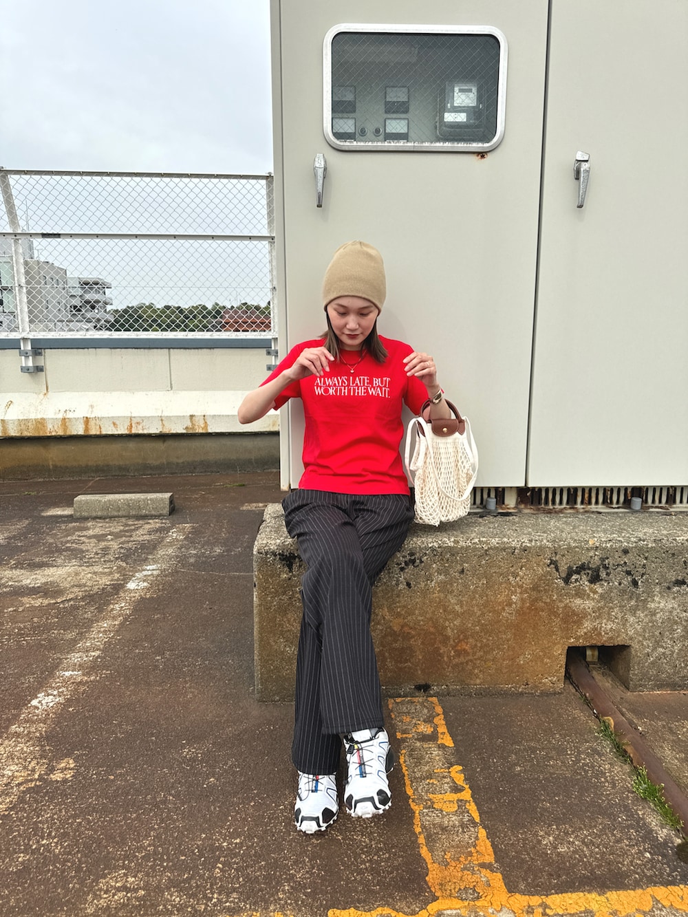 レッド系のTシャツ/カットソー、ブラック系のパンツ、ホワイト系のスニーカーを着用したレディースの夏コーディネートの2枚目の写真