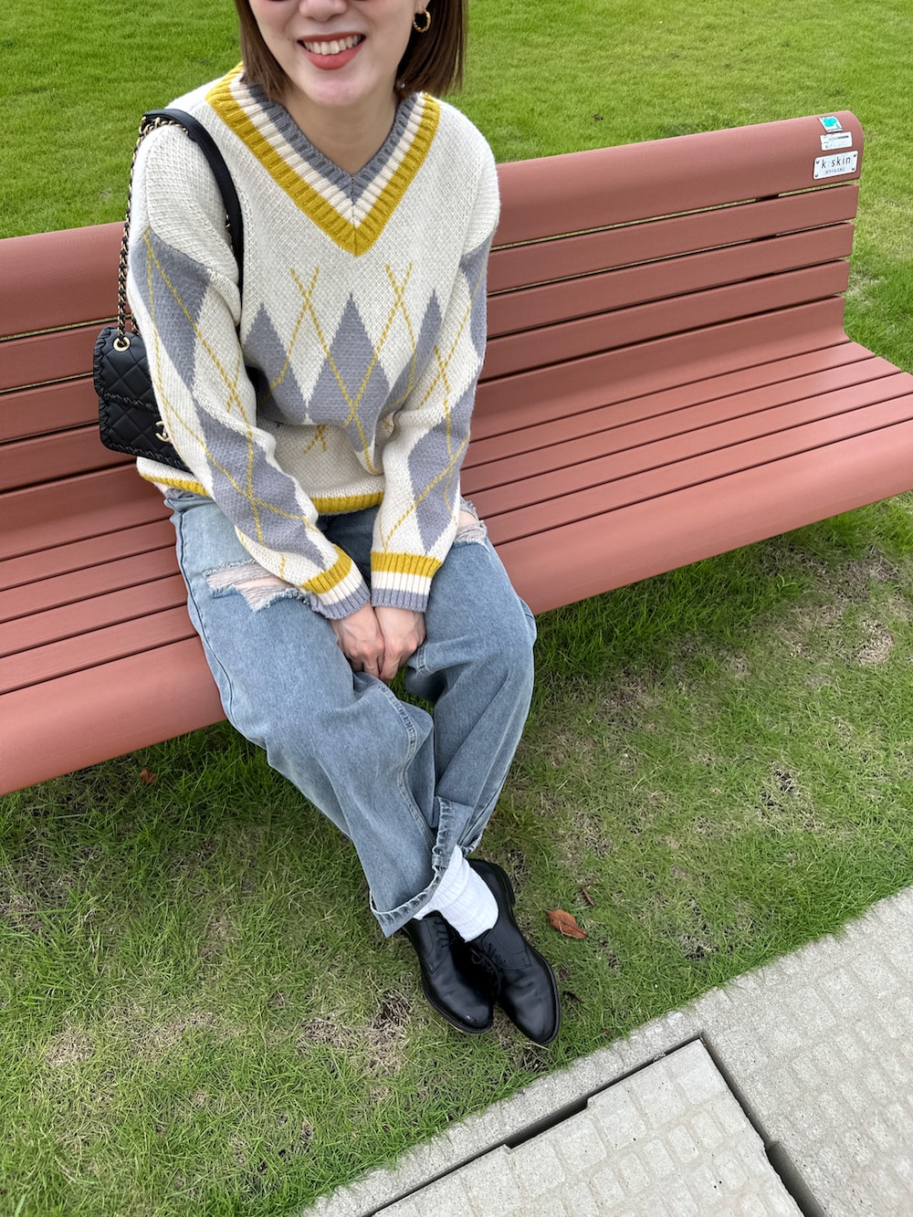 ブルー系のデニムパンツ、ベージュ系のニット/セーター、ブラウン系のメガネを着用したレディースの秋コーディネートの2枚目の写真