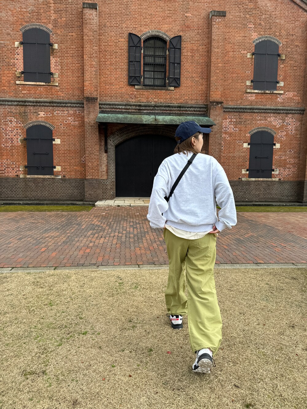 グリーン系のパンツ、グレー系のスウェット、ブラック系のバッグを着用したレディースの春コーディネートの2枚目の写真