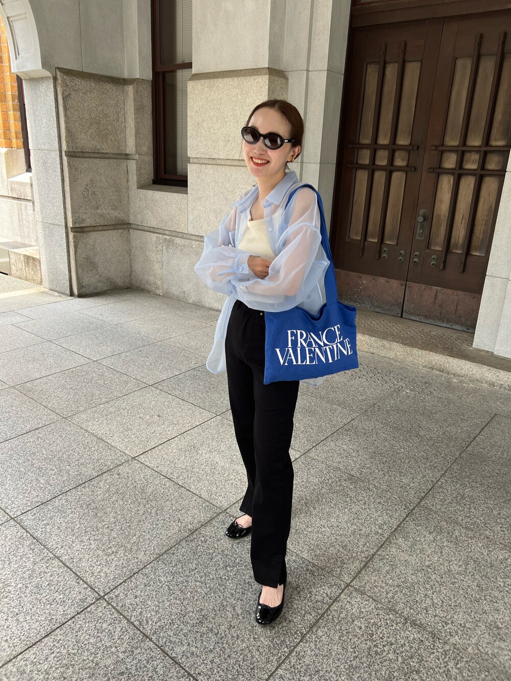 ブラック系のデニムパンツ、ブラック系のバレエシューズ、ブルー系のトートバッグを着用したレディースの夏コーディネートの3枚目の写真