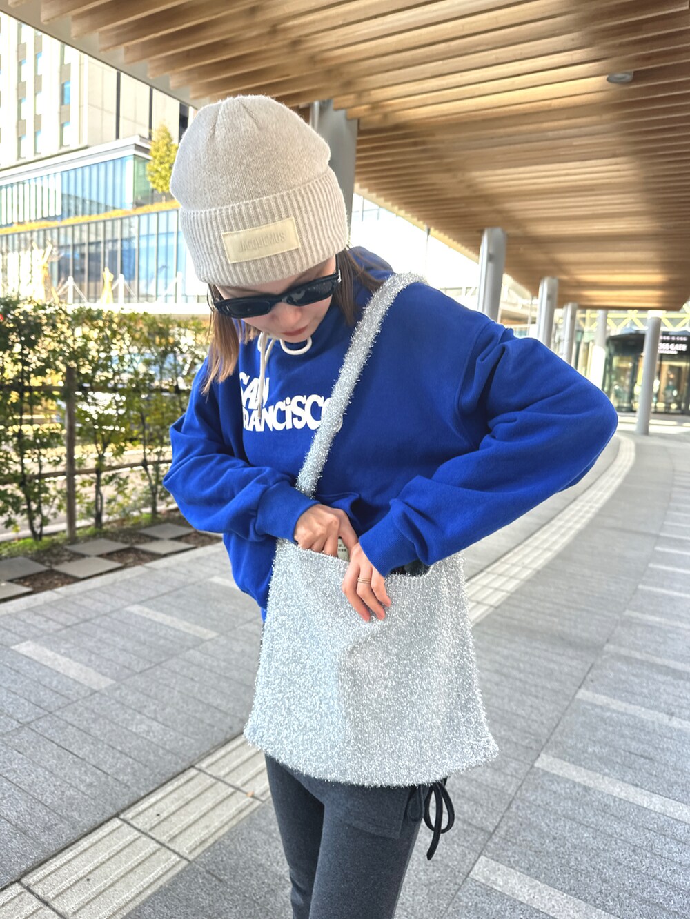 グレー系のパンツ、シルバー系のバッグ、ブラック系のスニーカーを着用したレディースの冬コーディネートの2枚目の写真