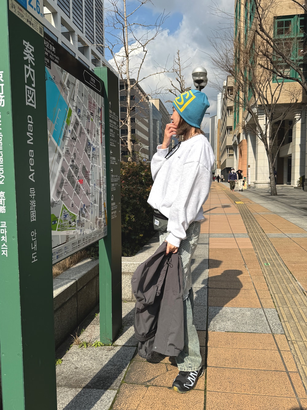 グレー系のスウェット、ホワイト系のスカート、ブルー系のデニムパンツを着用したレディースの冬コーディネートの2枚目の写真