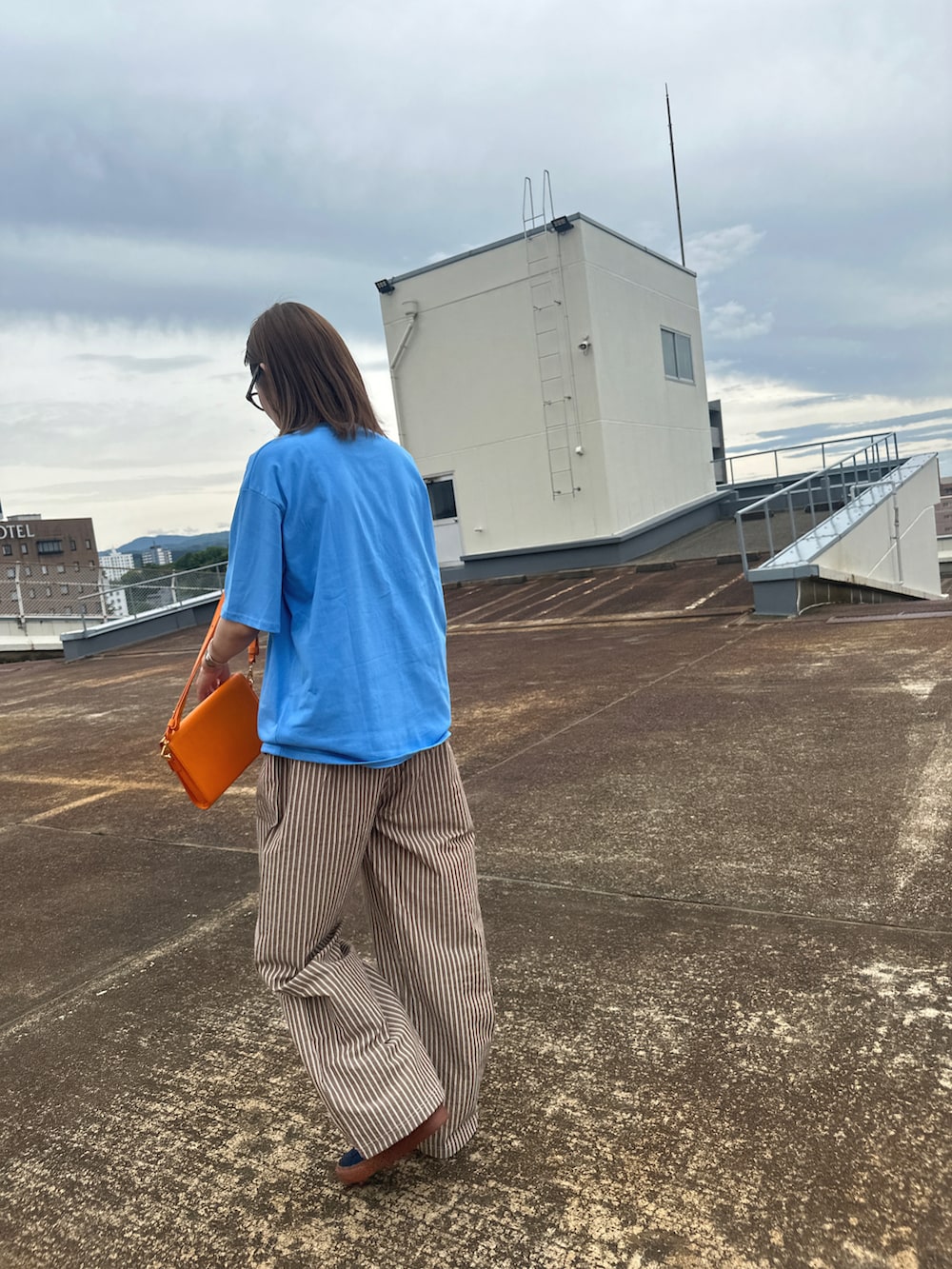 ブルー系のTシャツ/カットソー、ブラウン系のパンツ、ブラウン系のメガネを着用したレディースの春コーディネートの3枚目の写真