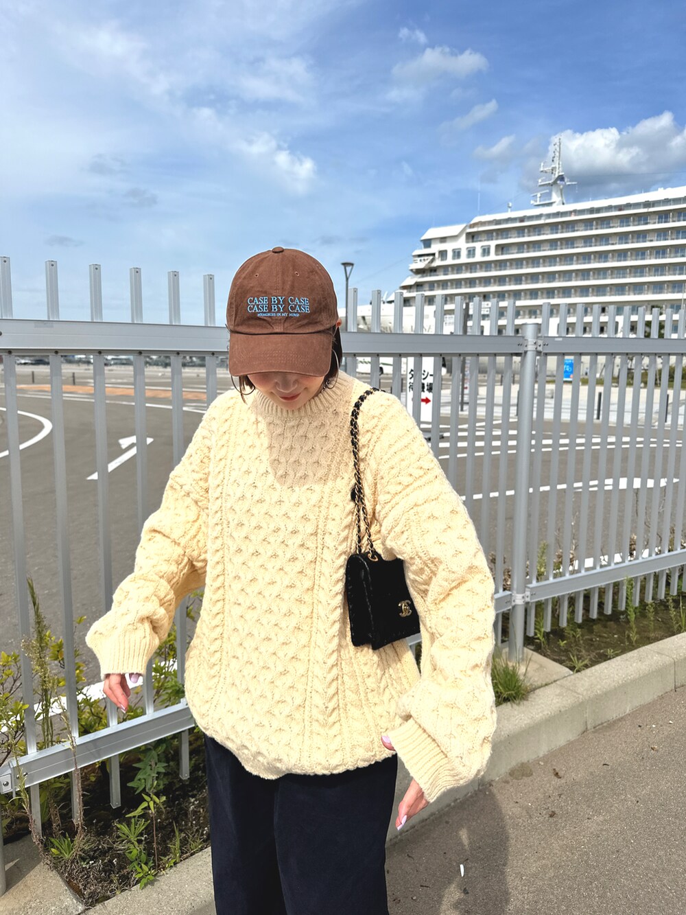 ブルー系のパンツ、ベージュ系のニット/セーター、ブラウン系の帽子を着用したレディースの秋コーディネートの3枚目の写真