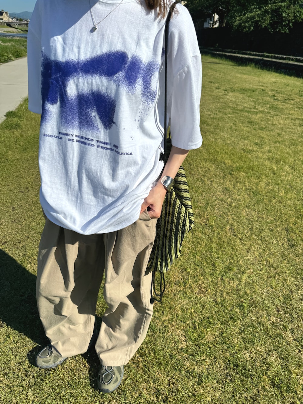 ホワイト系のTシャツ/カットソー、ベージュ系のパンツ、グリーン系のスニーカーを着用したレディースの春コーディネートの3枚目の写真